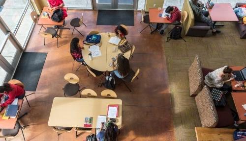 哈内德大厅休息区的俯视图，许多学生分组在不同的桌子上单独或在公司工作.